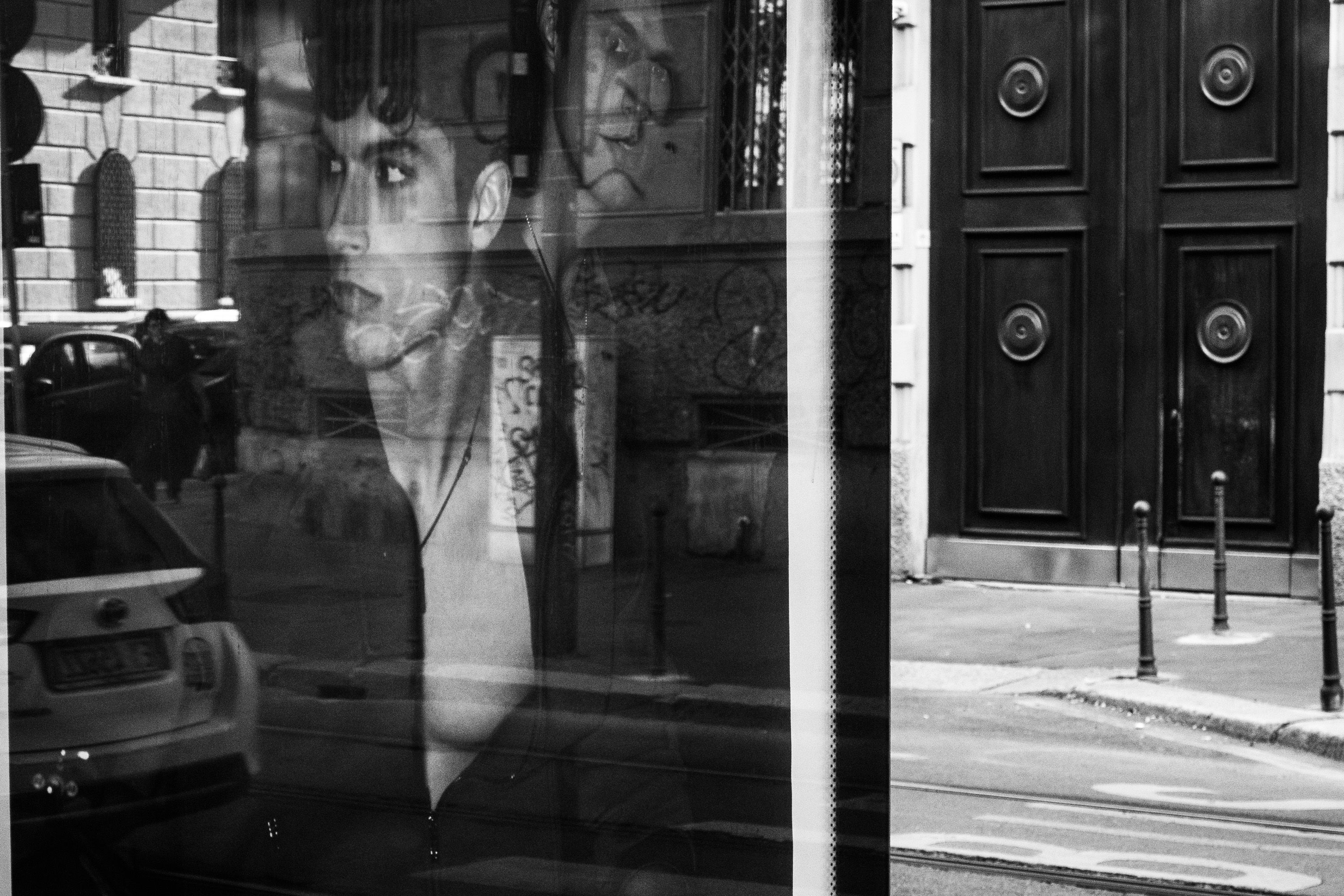 Il riflesso di una pubblicità di moda in strada e un portone sullo sfondo