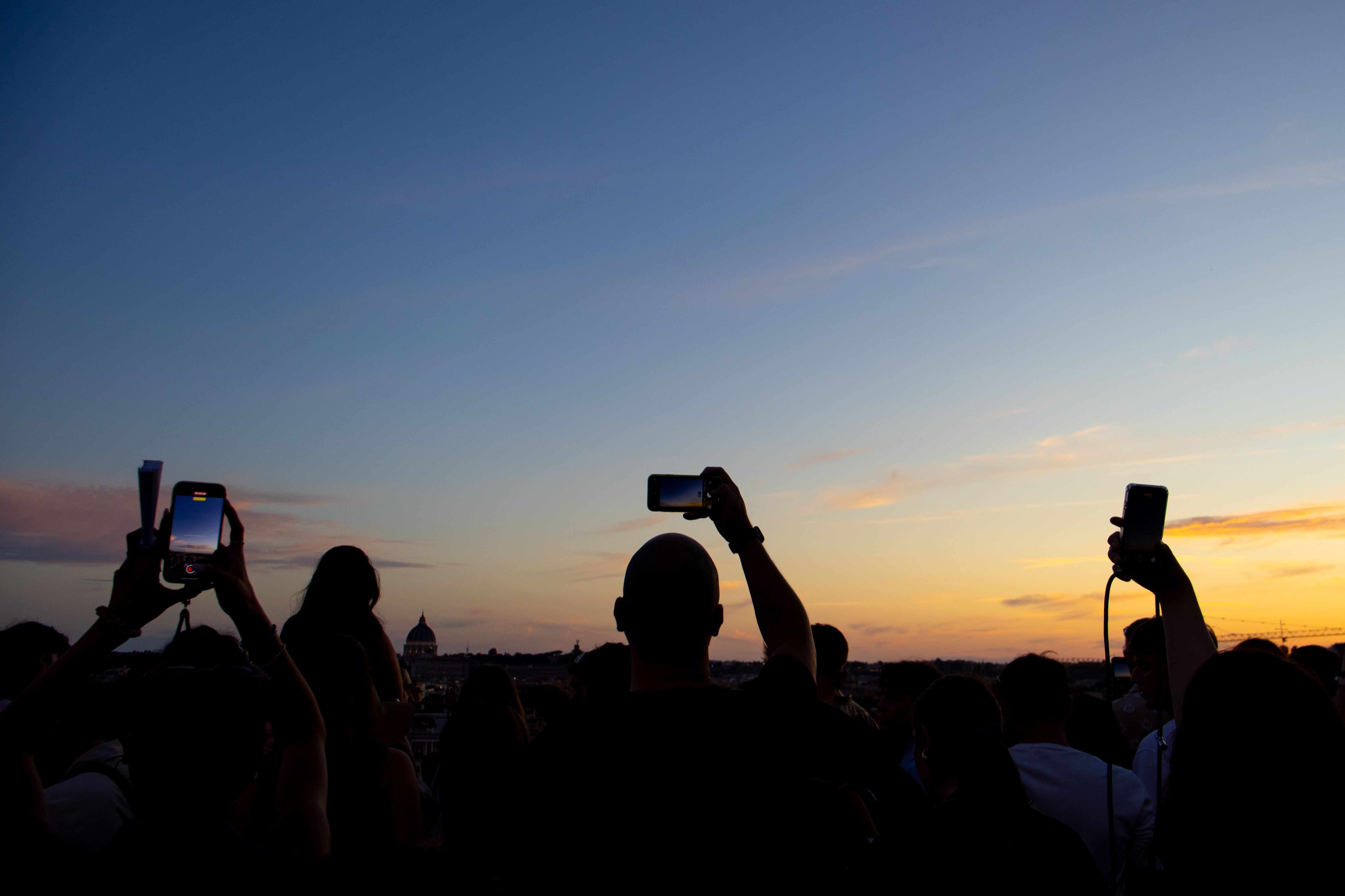 Persone che con il cellulare in mano fotografano il tramonto