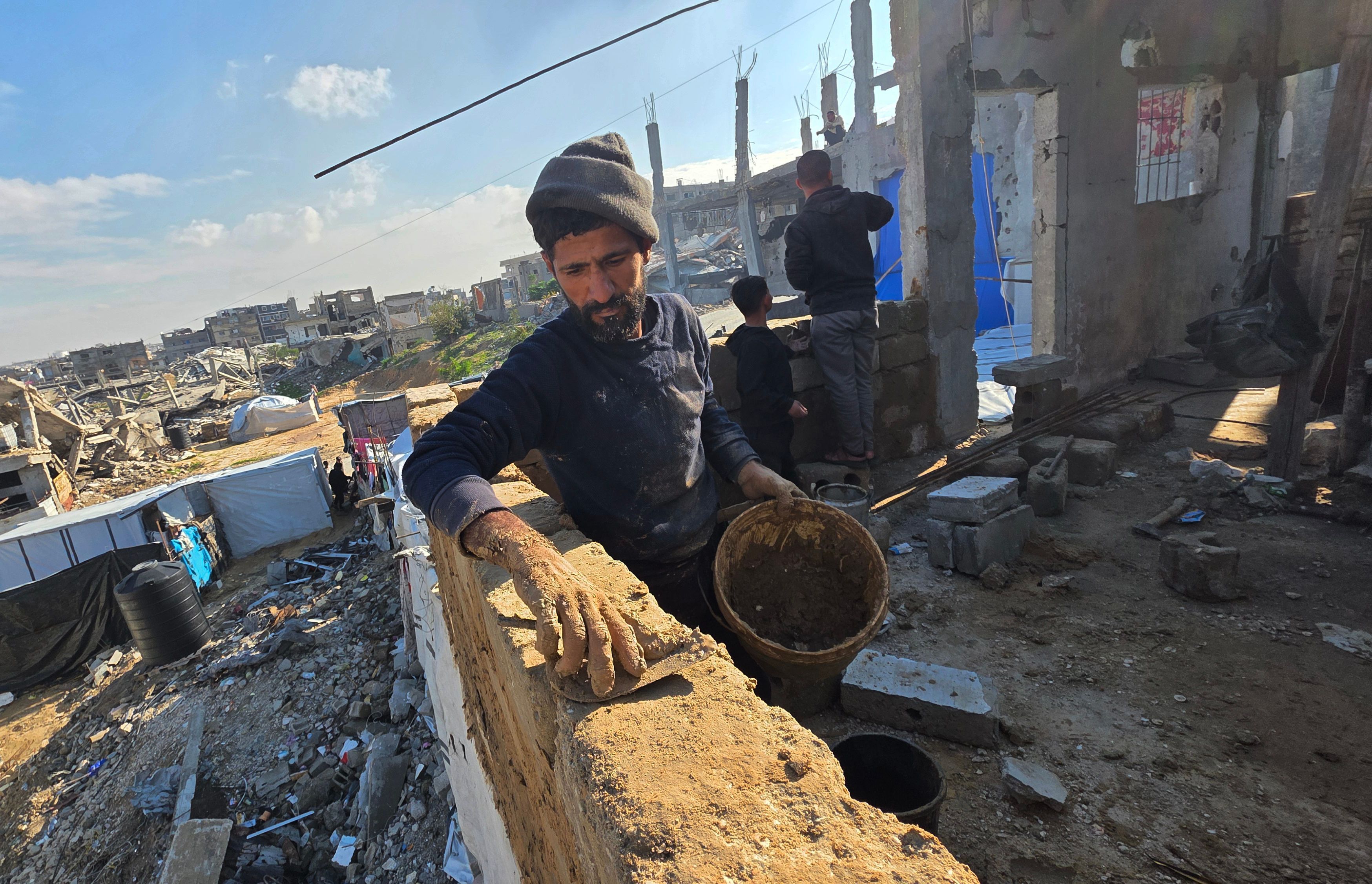Per qualche ora ha smesso di piovere e i palestinesi di Khan Yunis hanno iniziato a costruire ripari di fango, utilizzando strumenti e metodi rudimentali, per cercare di garantirsi una protezione dal freddo invernale /Fotogramma