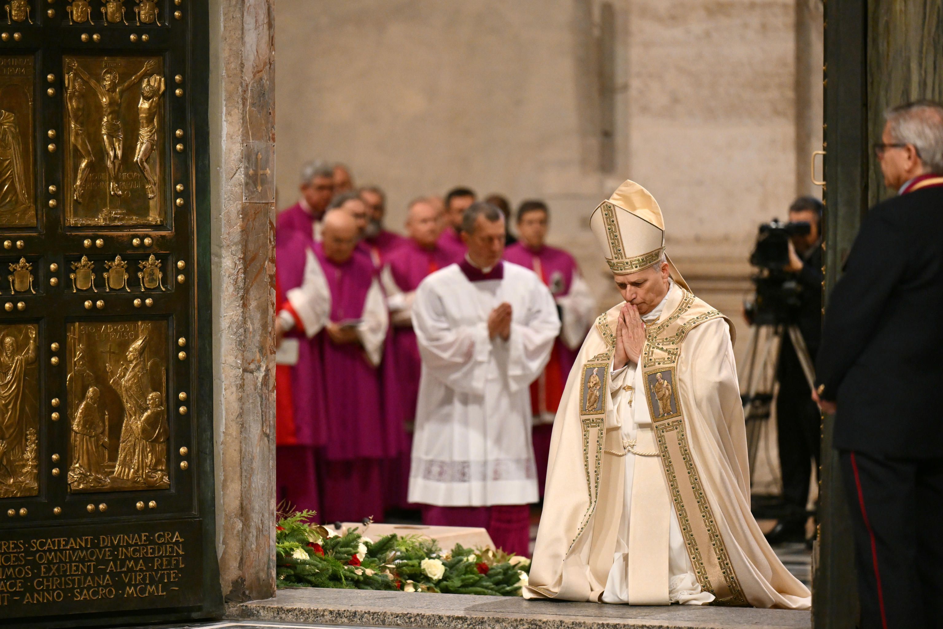 Papa Leone XIV inginocchiato davanti alla Porta Santa nella Basilica di San Pietro / ANSA