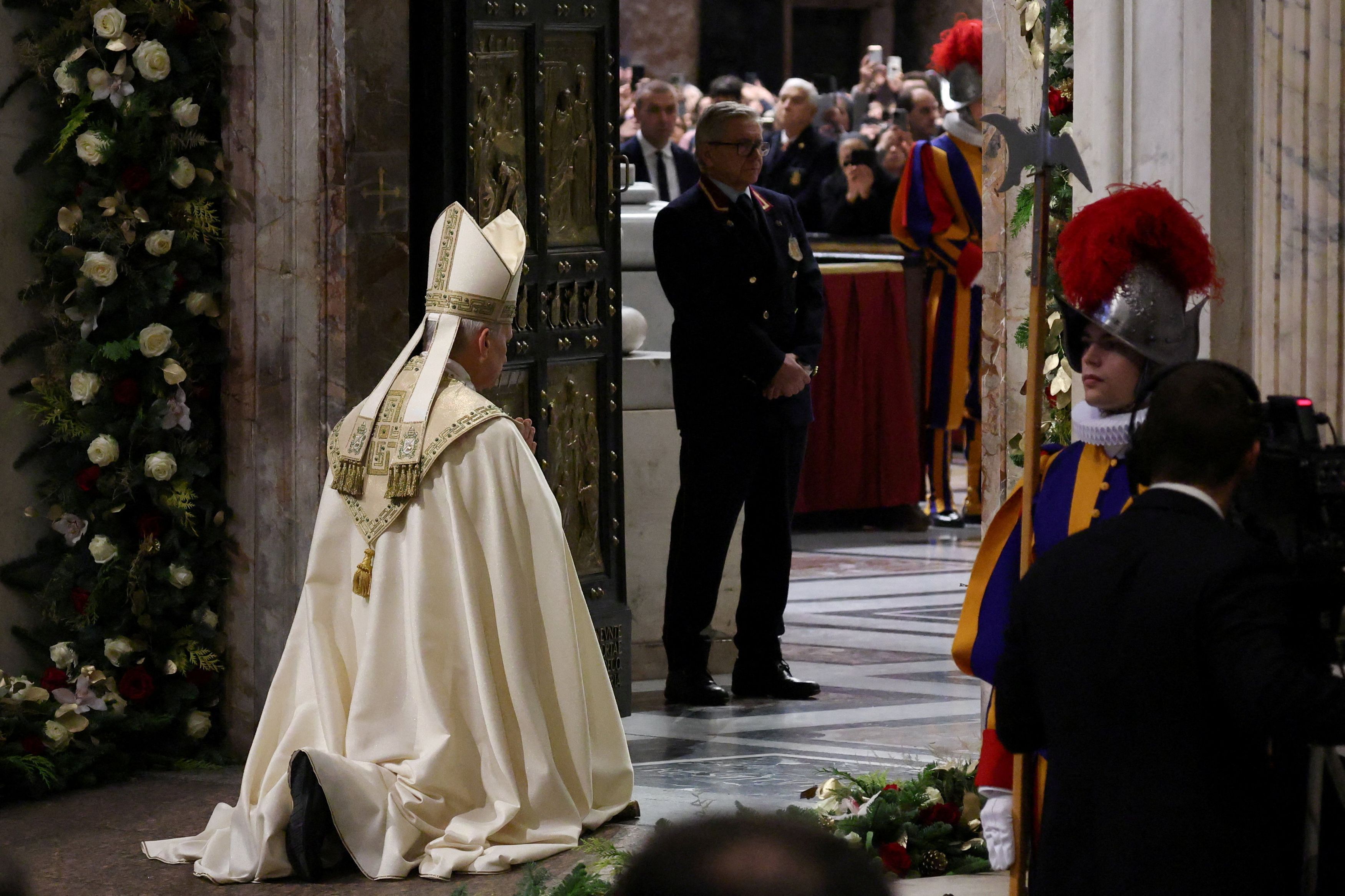 Papa Leone XIV inginocchiato davanti alla Porta Santa nella Basilica di San Pietro / REUTERS