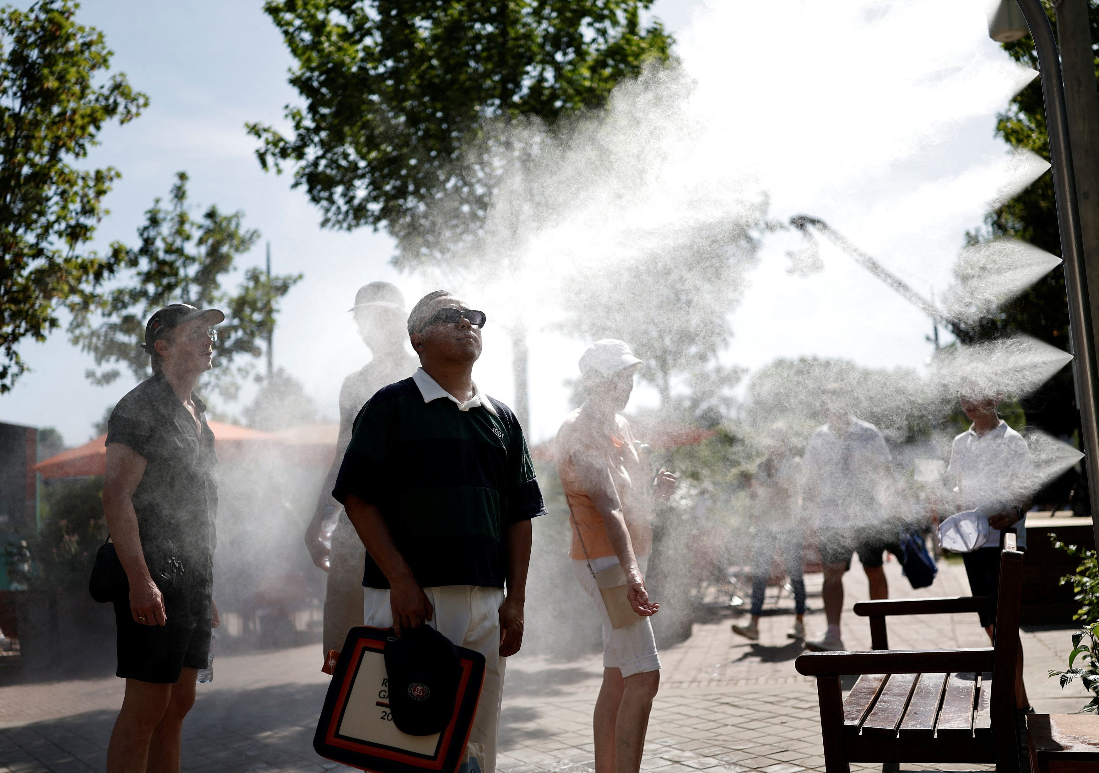 Gli spettatori del Roland Garros a Parigi si rinfrescano presso una postazione con spruzzi d'acqua. (Foto di BENOIT TESSIER /REUTERS)