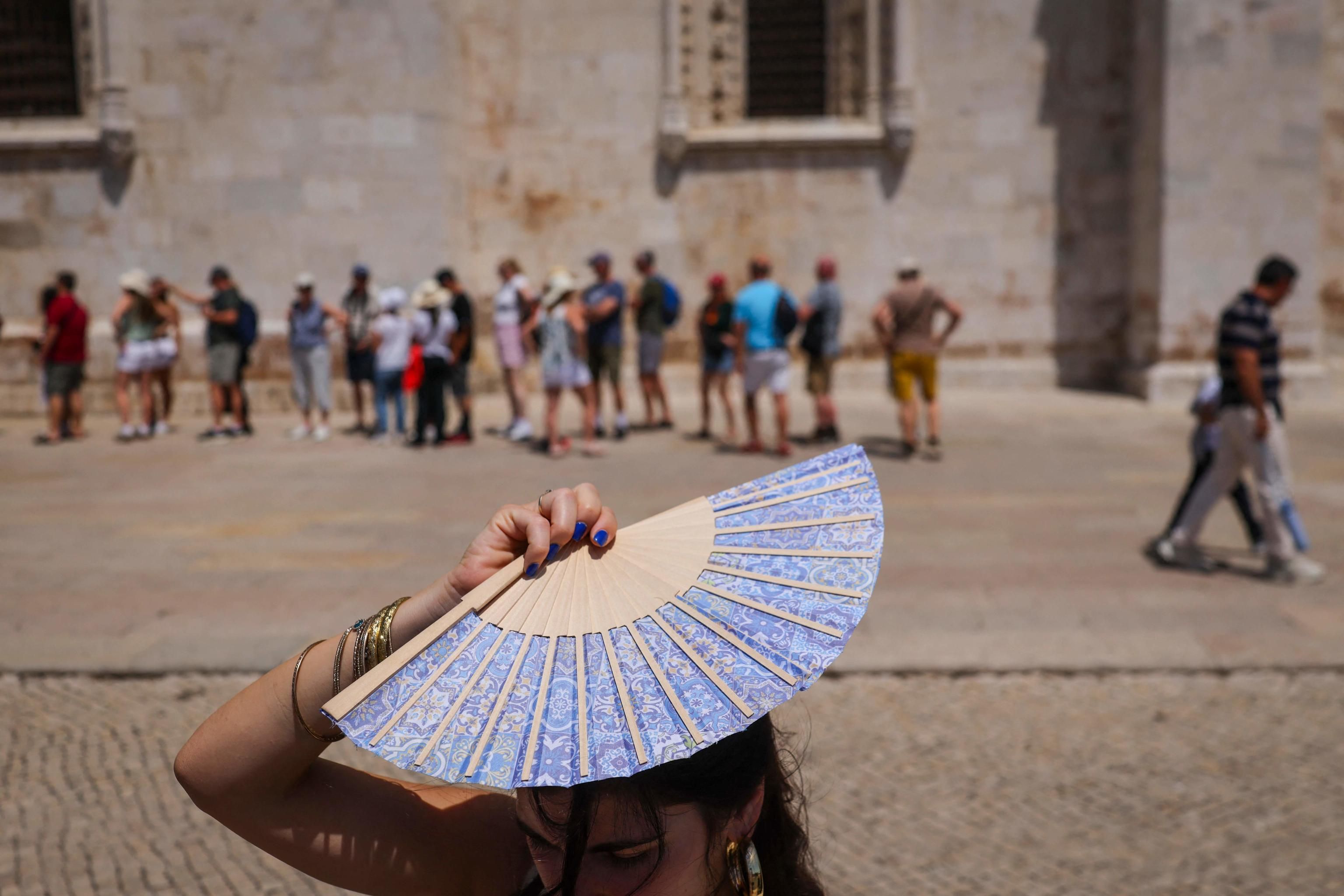 Una donna si ripara il viso con un ventaglio davanti al Monastero dos Jerónimos a Belém, in Portogallo (Foto di PATRICIA DE MELO MOREIRA / AFP)