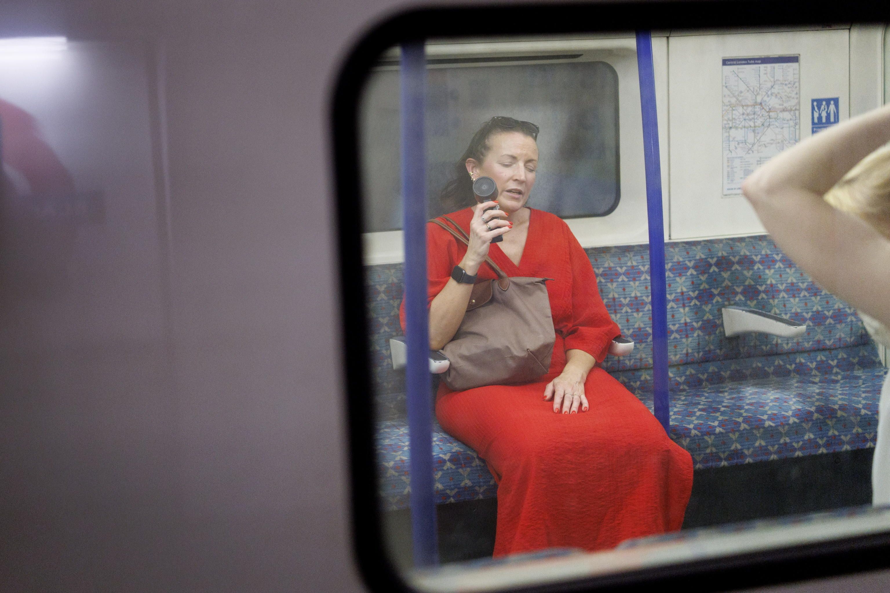 Una persona utilizza un ventilatore elettrico per rinfrescarsi nella metropolitana di Londra. (Foto di TOLGA AKMEN /EPA)