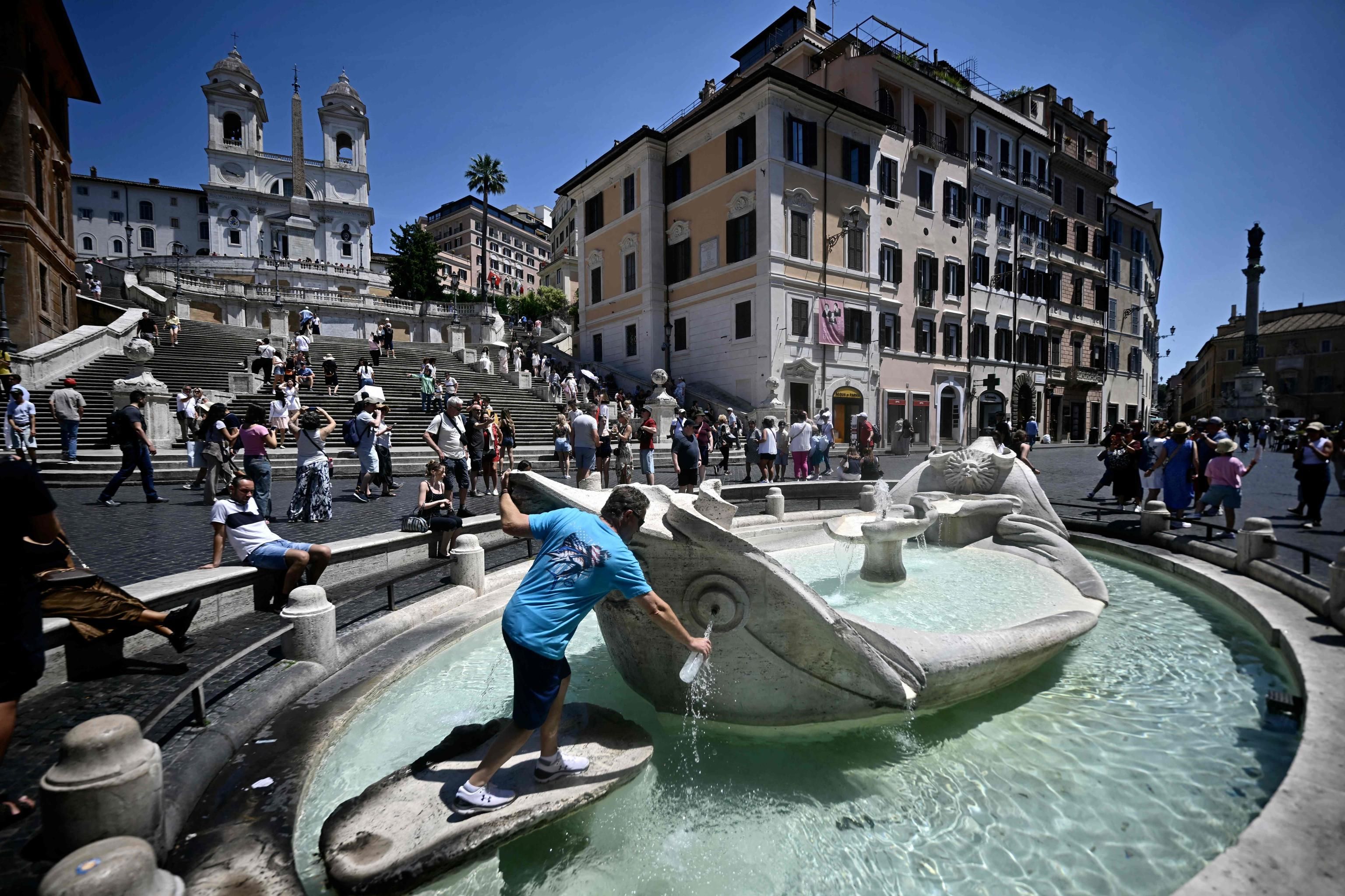 Un uomo riempie una bottiglia d'acqua alla fontana della Barcaccia in Piazza di Spagna a Roma. (Foto di FILIPPO MONTEFORTE / AFP)
