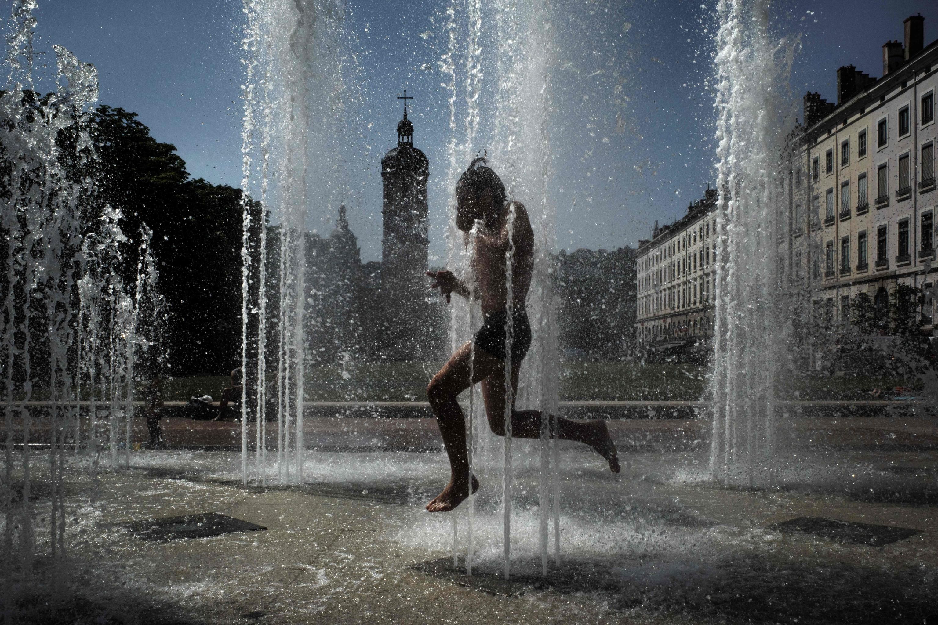 Un bambino si rinfresca in una fontana a Lione, in Francia /ANSA