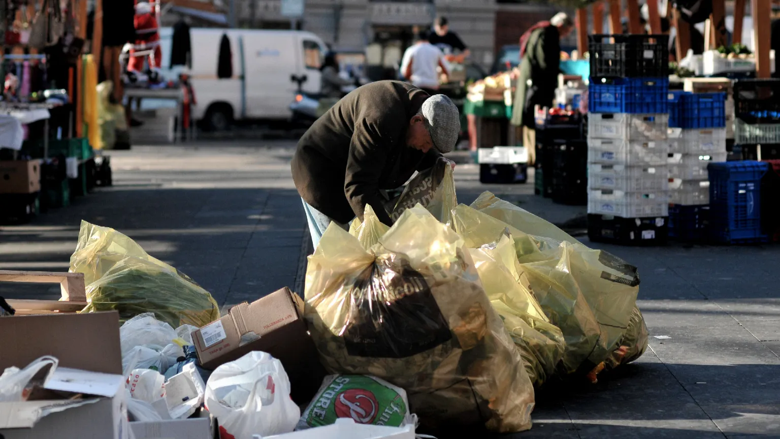 Un anziano fruga tra i rifiuti del mercato di piazza S. Cosimato a Trastevere, a Roma per cercare del cibo da mangiare