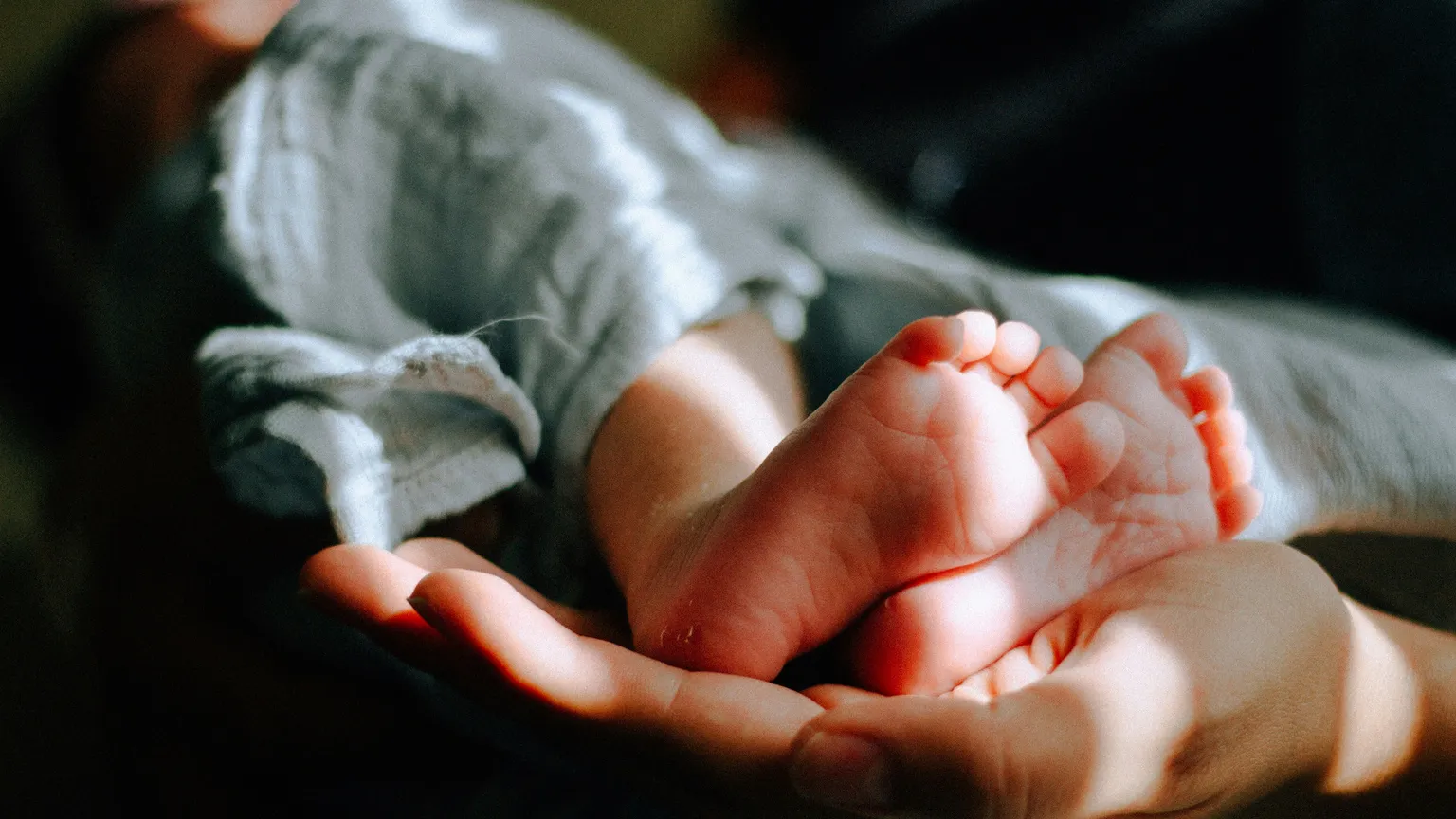 Una mamma tiene tra le mani i piedi del suo bambino. Foto d'archivio