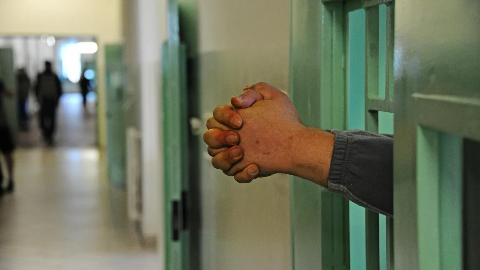 Due mani che sporgono dalle sbarre di un carcere