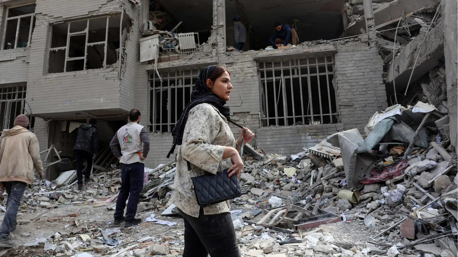 Una donna davanti a un edificio distrutto a Teheran