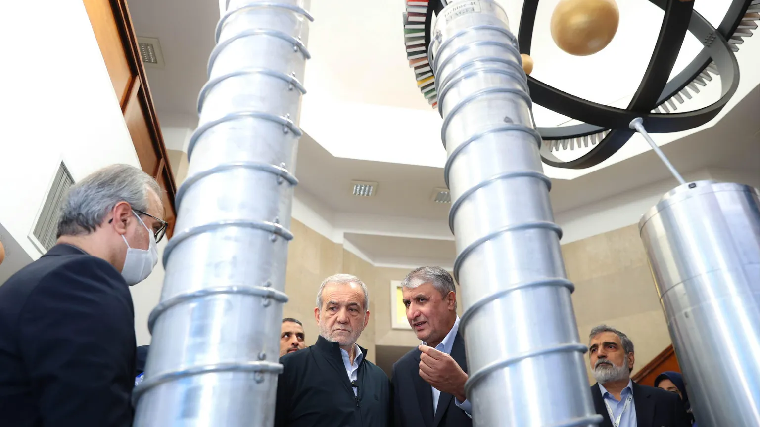Un gruppo di funzionari iraniani e il presidente Massud Pezeshkian ispezionano dei grandi cilindri grigi in uno degli impianti del programma nucleare