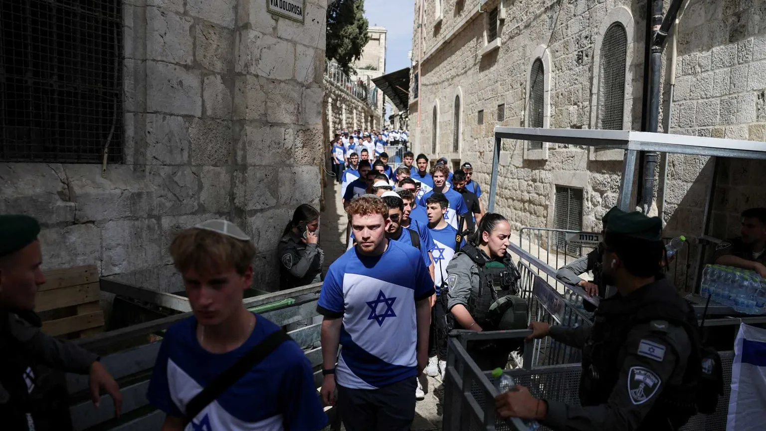 In un vicolo stretto della Città Vecchia una lunga fila di giovani che indossano magliette con la bandiera di Israele, bianche e celesti con la Stella di David, passano attraverso un controllo di polizia
