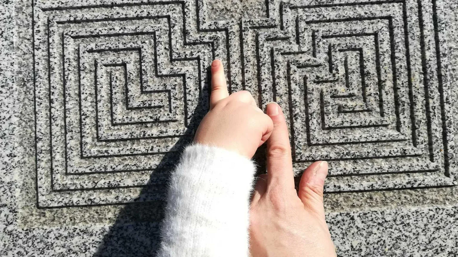 Due dita si muovono su un labirinto di pietra