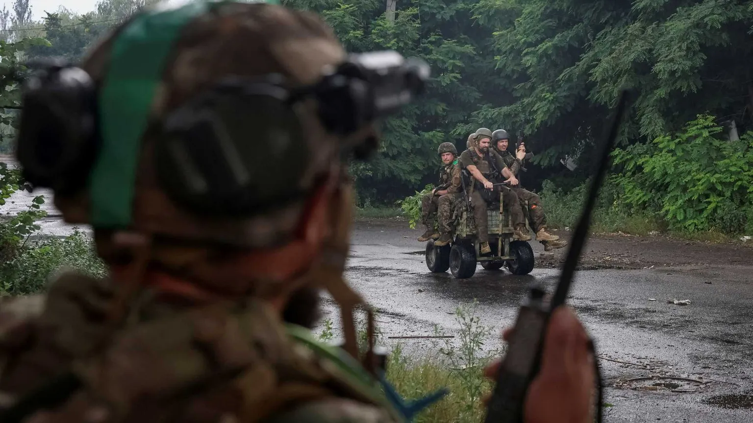 Quattro militari su un mezzo. In primo piano, sfocato, un militare di spalle che parla a un radio trasmettitore