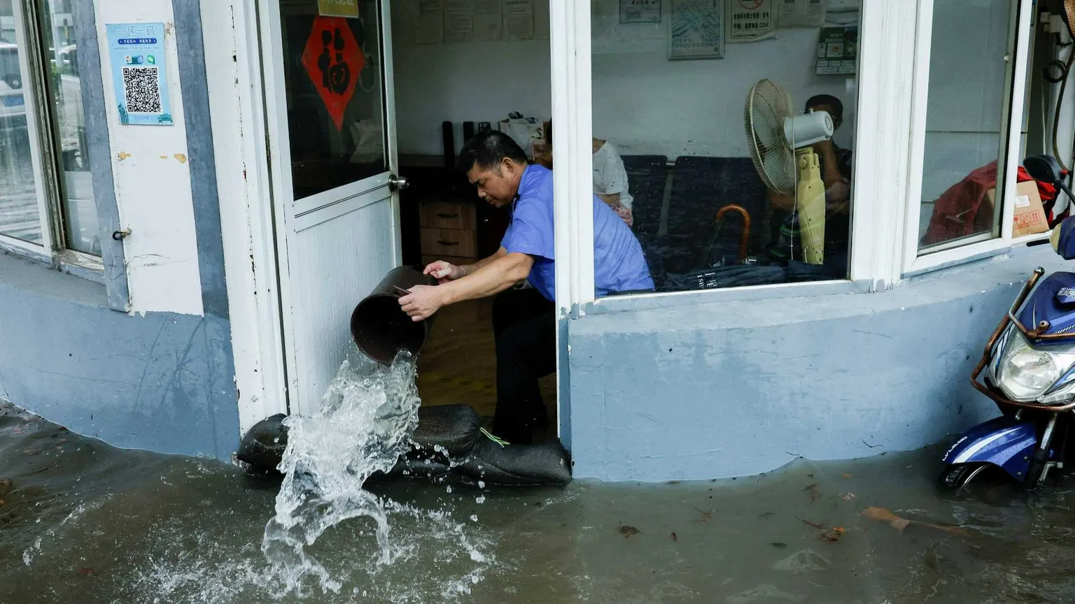 Un uomo usa un secchio per buttare acqua fuori dal suo negozio