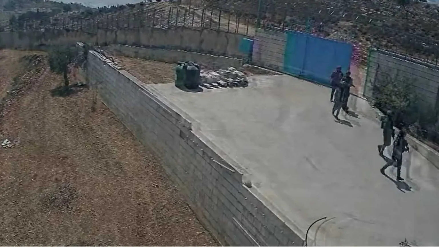 Soldati che fanno irruzione dentro a un cancello. Visti da lontano