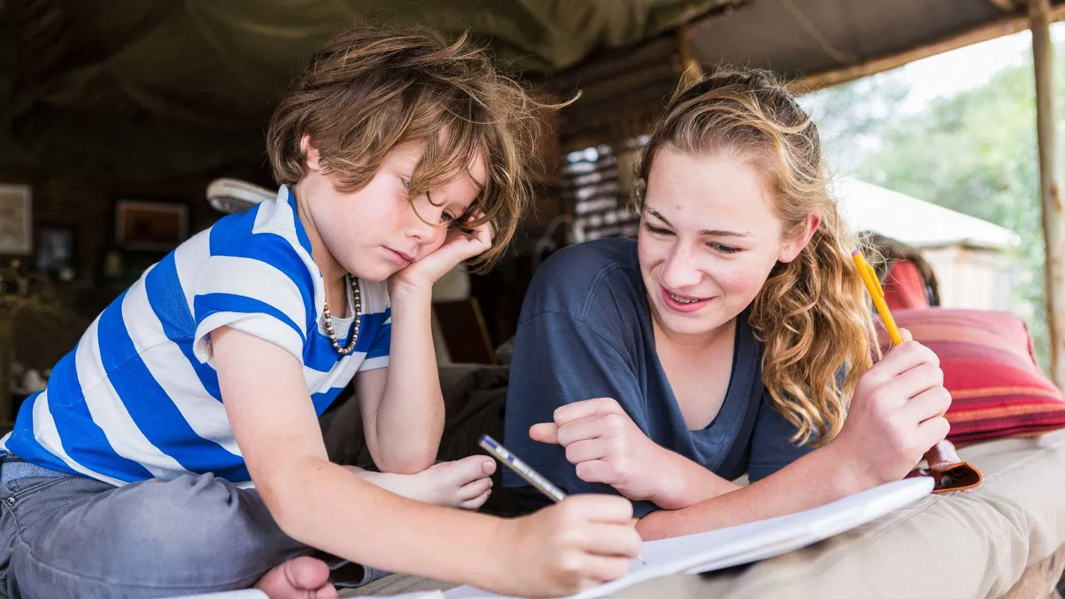 Fratello e sorella fanno i compiti della vacanze in tenda in Francia