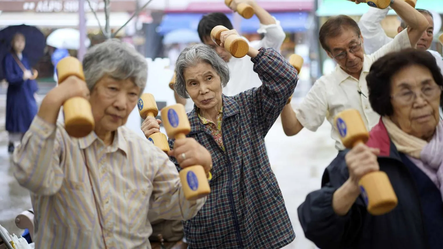 Anziani praticano attività fisica con manubri di legno durante un evento per la "Giornata di rispetto per gli anziani" a Tokyo