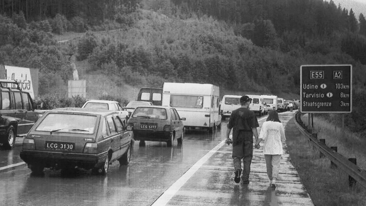 Una foto del 1996 scattata al confine tra Italia e Austria. Una coppia passeggia lungo la strada, bloccata da file interminabili di auto