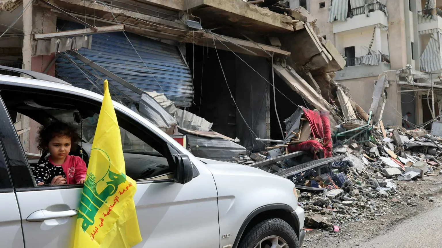Un’auto con la bandiera gialla di Hezbollah si sposta fra le macerie di Nabatieh, nel Libano meridionale/ ANSA