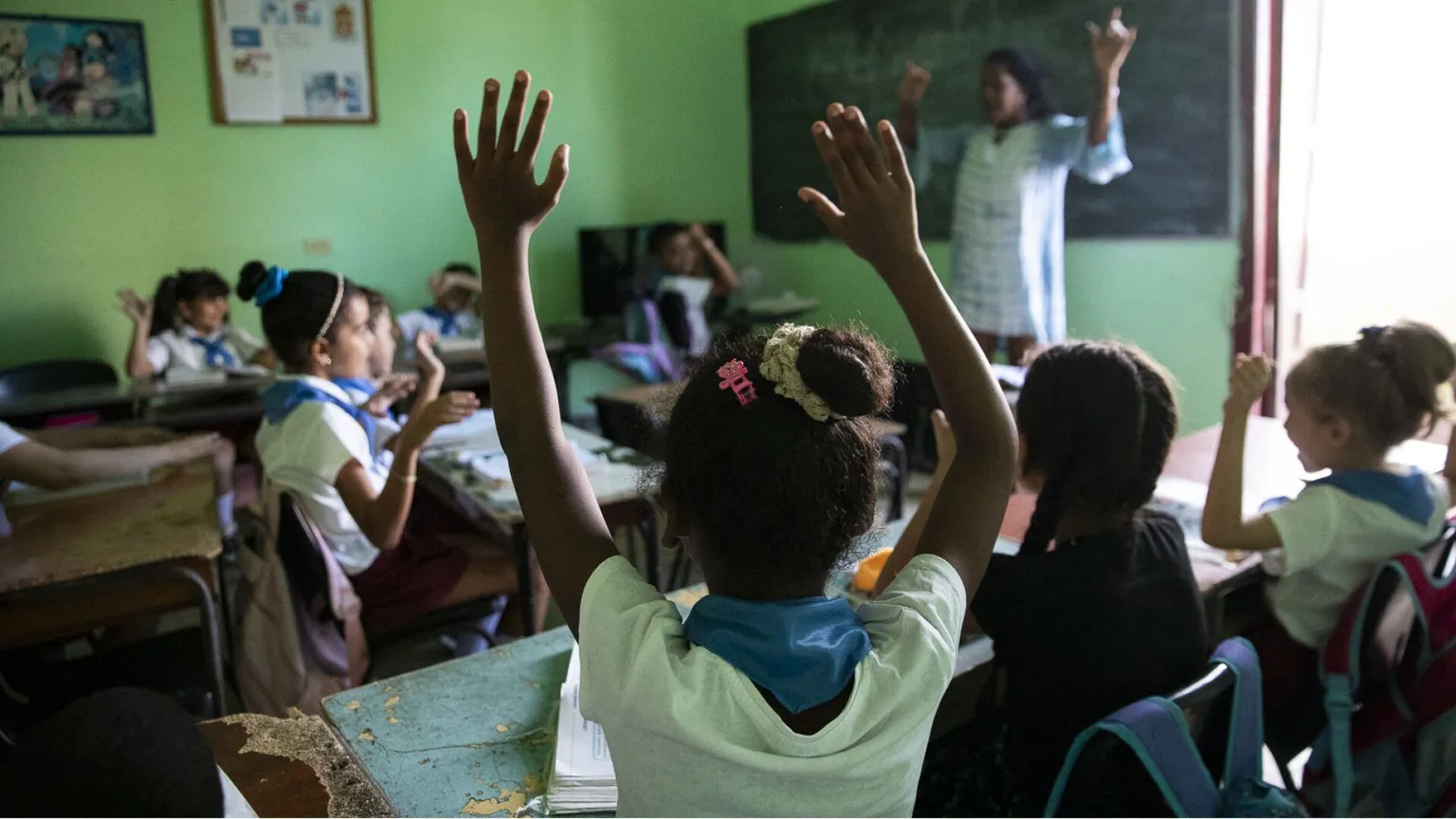Bambini alzano le mani in classe