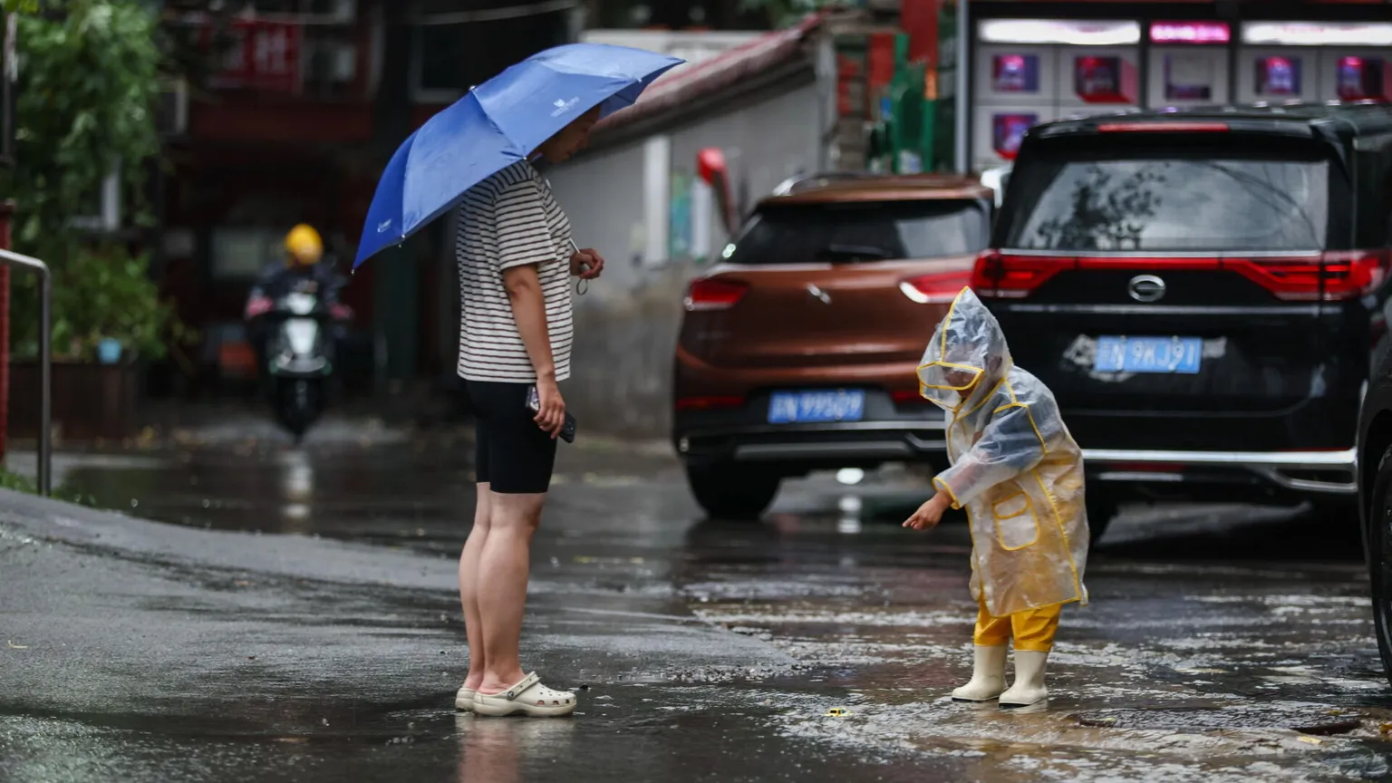 Mamma e figlia in strada sotto la pioggia