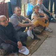 Nella fotto si vedono l’arcivescovo di Milano Mario Delpini seduto a terra in un villaggio beduino con altri partecipanti al recente pellegrinaggio in Terra Santa