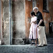 Una badante accompagna un anziano signore per le vie di Roma