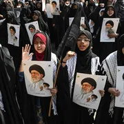 Una folla di donne con il lungo abito nero e la testa velata tengono in mano fotografie di Khamenei in segno di protesta