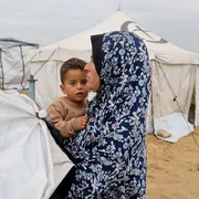 Una donna con in braccia il figlio in una tendopoli per sfollati a Khan Younis, nel sud della Striscia di Gaza