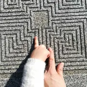 Due dita si muovono su un labirinto di pietra