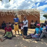Donne e uomini seduti davanti a una capanna tradizionale di canne nel villaggio di Nannona, nella provincia mozambicana di Cabo Delgado