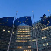 Bandiere con le stelle dell'Ue sventolano davanti a un edificio alto