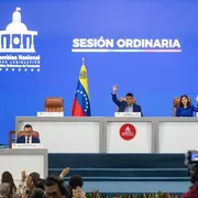 Un lungo tavolo bianco con la bandiera venezuelana e due persone sedute
