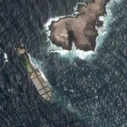 Dal satellite, l'immagine di una nave in mare poco distante da una penisola. Sulla nave è visibile una zona verde: sono alghe