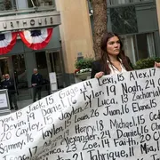 Una donna mostra un cartello con i nomi di bambini e giovani adulti le cui morti sono state collegate all’uso dei social media