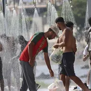 Alcuni migranti fanno la doccia sulla spiaggia di Trampolin a Ceuta