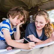 Fratello e sorella fanno i compiti della vacanze in tenda in Francia