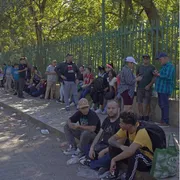 Gruppi di rifugiati in attesa seduti su n marciapiede di Città del Messico