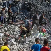 Una decina di persone, tra cui almeno 6 bambini, si muovono sulle macerie di un edificio crollato