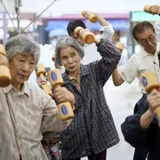 Anziani praticano attività fisica con manubri di legno durante un evento per la "Giornata di rispetto per gli anziani" a Tokyo