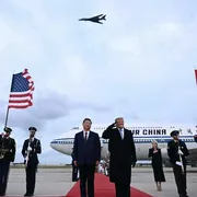 Il presidente degli Stati Uniti Donald Trump reagisce al passaggio di un bombardiere B-1 durante gli inni nazionali, mentre accoglie il presidente cinese Xi Jinping al suo arrivo alla Joint Base Andrews