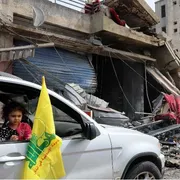 Un’auto con la bandiera gialla di Hezbollah si sposta fra le macerie di Nabatieh, nel Libano meridionale/ ANSA