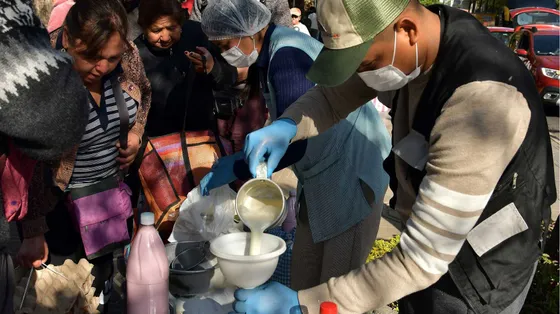 Un uomo versa del latte in un contenitore in mezzo alla folla
