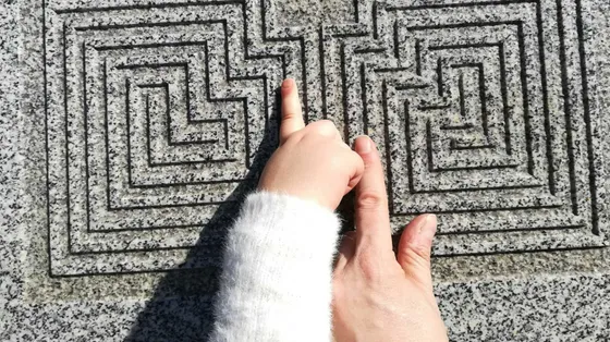Due dita si muovono su un labirinto di pietra