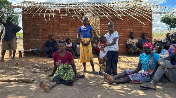 Donne e uomini seduti davanti a una capanna tradizionale di canne nel villaggio di Nannona, nella provincia mozambicana di Cabo Delgado