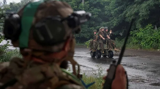 Quattro militari su un mezzo. In primo piano, sfocato, un militare di spalle che parla a un radio trasmettitore