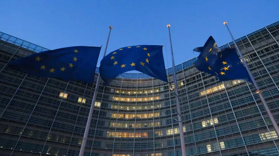 Bandiere con le stelle dell'Ue sventolano davanti a un edificio alto