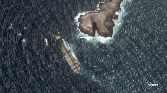Dal satellite, l'immagine di una nave in mare poco distante da una penisola. Sulla nave è visibile una zona verde: sono alghe