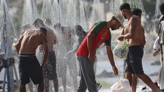 Alcuni migranti fanno la doccia sulla spiaggia di Trampolin a Ceuta